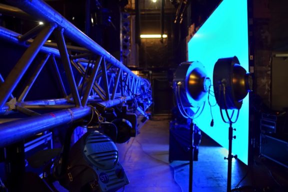 Bühnenaufbau mit Scheinwerfern und beleuchtetem, blauen Hintergrund.